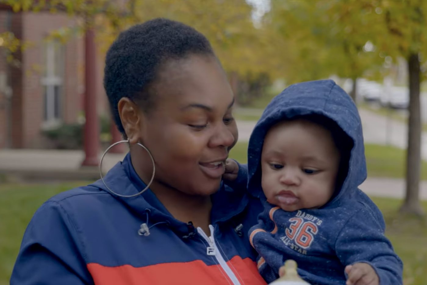 A mother holding her infant son outdoors